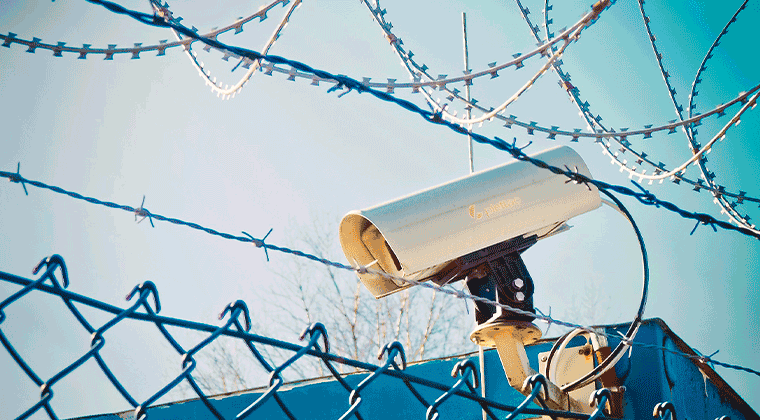 Uma câmera de segurança montada em cima de uma cerca de metal
