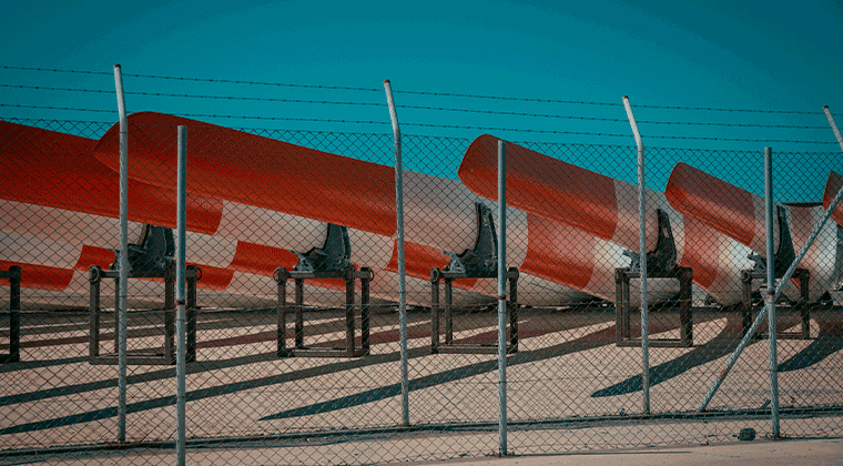 Uma fileira de aviões vermelhos e brancos atrás de uma cerca elétrica