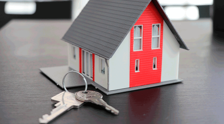Um modelo de casa com uma chave sobre uma mesa