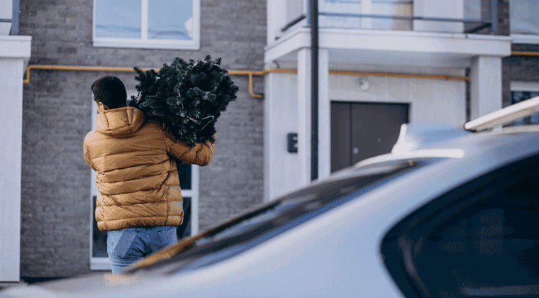 Um homem carregando um monte de folhas verdes nas costas