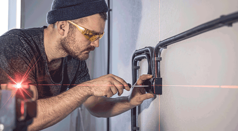 Um homem trabalhando em uma parede com um laser