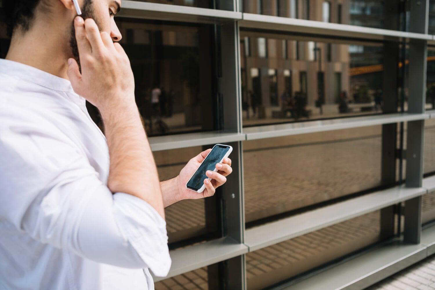 Homem na rua recebendo notificação de alarme no seu celular