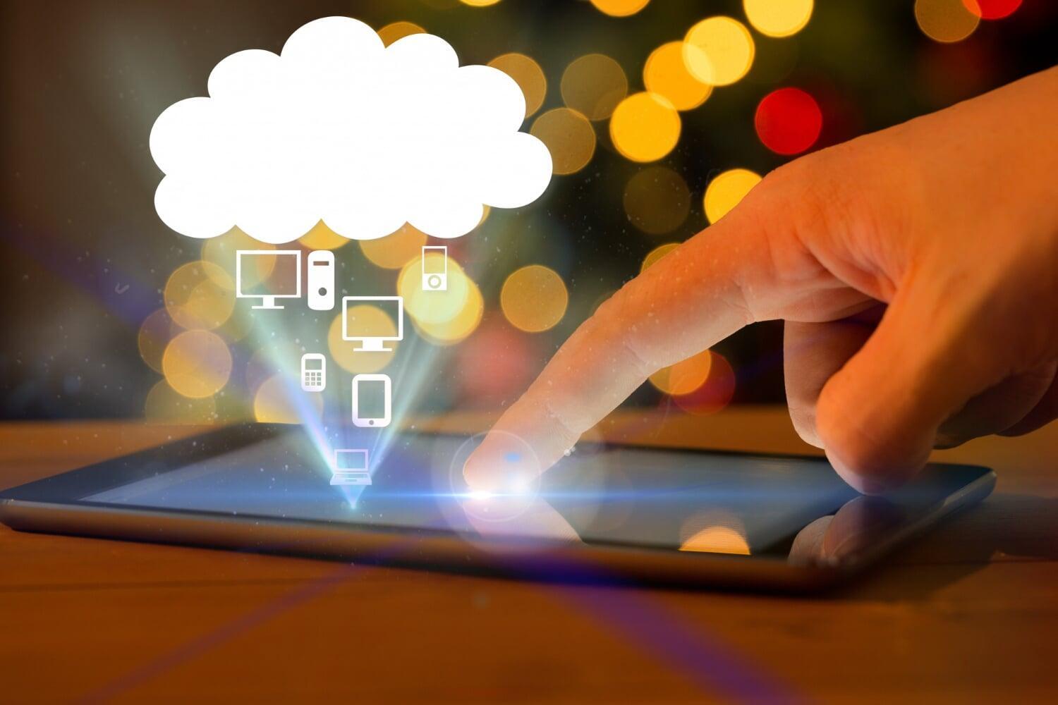 Pessoa tocando uma tela de tablet com ícones de dispositivos conectados à nuvem