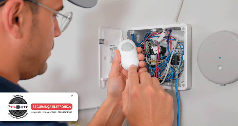 Técnico segurando sensor de movimento próximo a central de fiação
